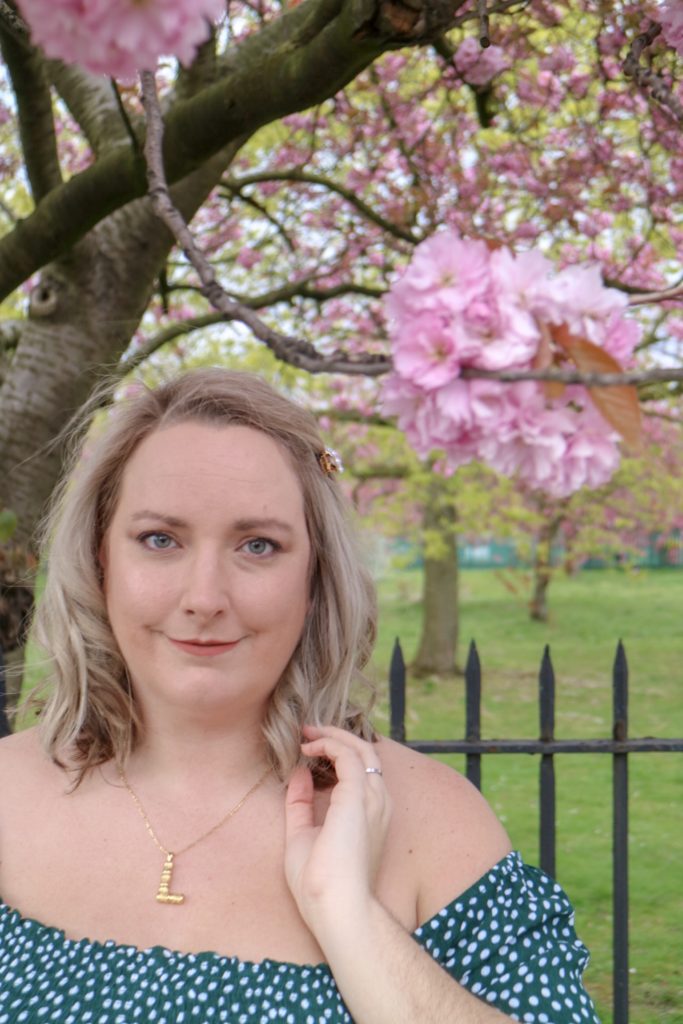 lucy with grey hair stood in front of a blossom tree