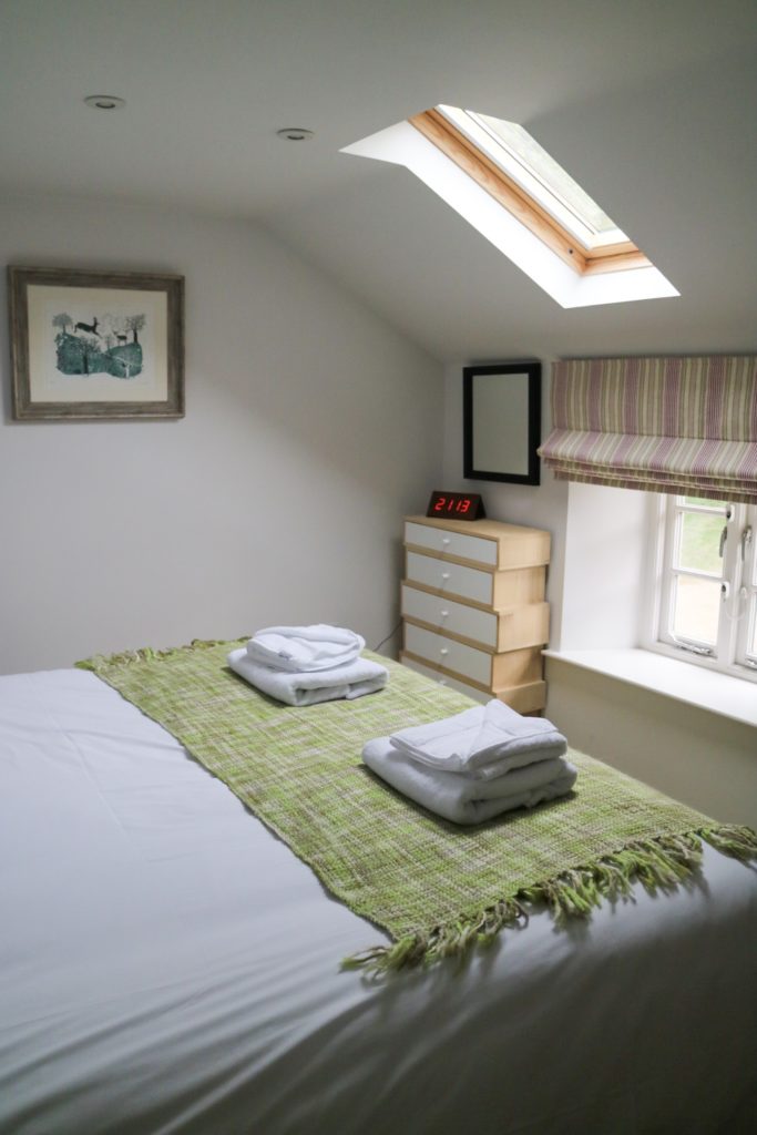 towels on bed and a window and skylight 