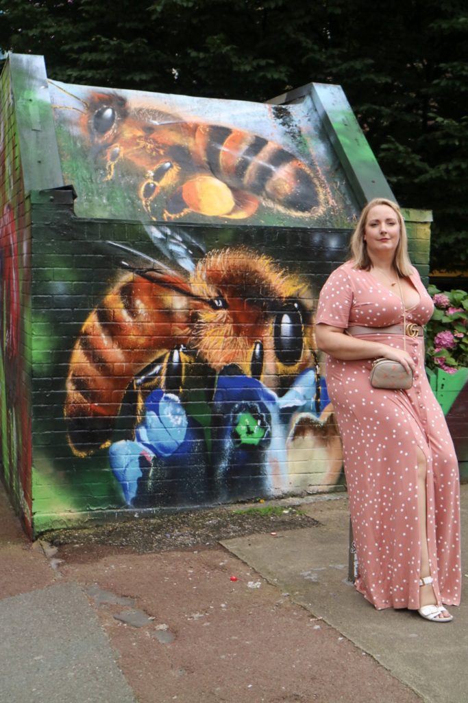 lucy sat in front of bee street art in manchester