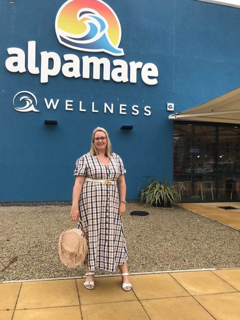 lucy in a check maxi dress stood in front of the alpamare sign
