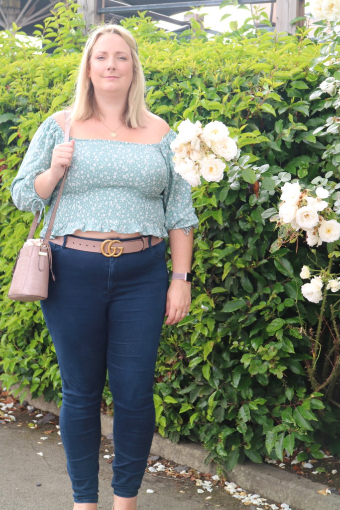 lucy in a green bardot top, jeans and pink gucci belt
