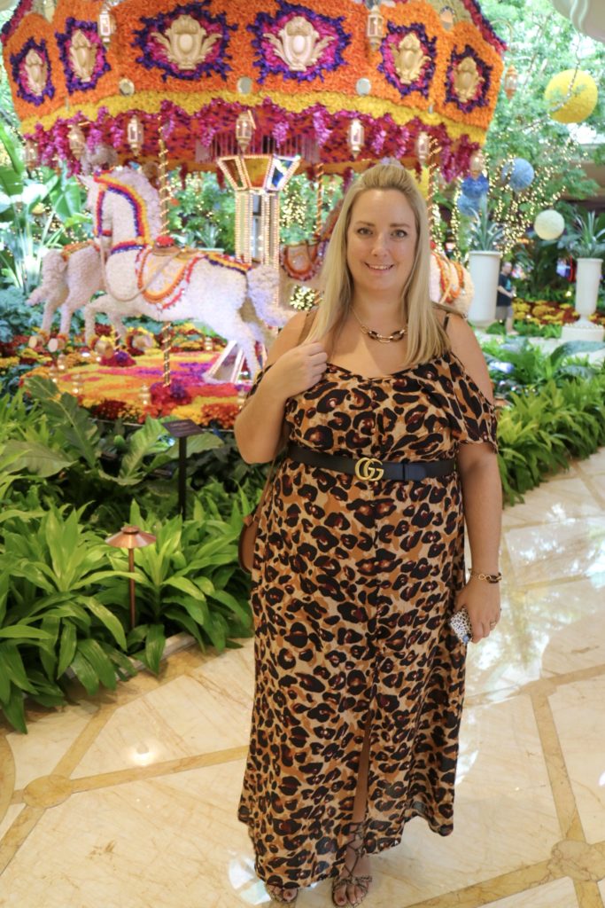 lucy in a leopard print dress in front of a flroal carousel display in The Wynn Las Vegas