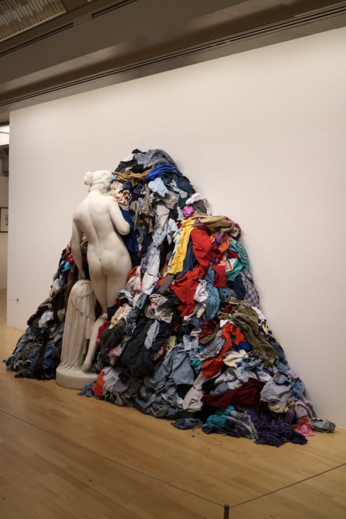 art at the tate liverpool- a statue facing the wall surrounded by scraps of clothes