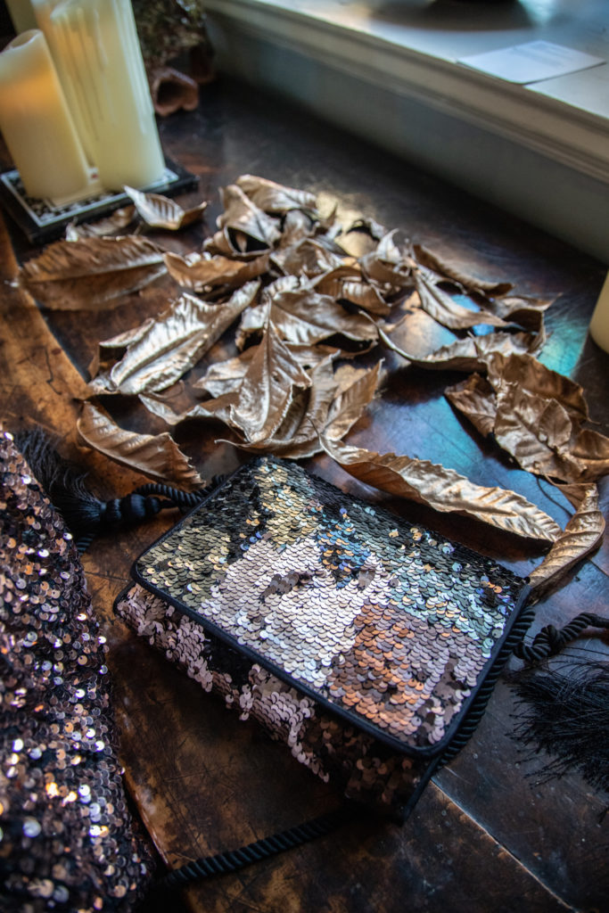 sequin bag surrounded by gold leaves