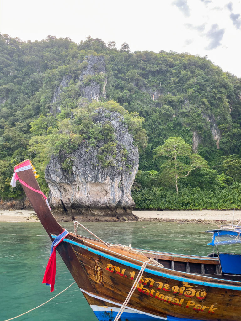a traditional thai boat with cliffs behind it
