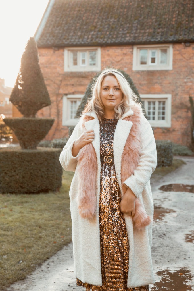 lucy outside in a sequin dress and cream coat