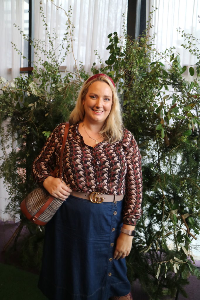 lucy in front of a foliage wall in a top and skirt