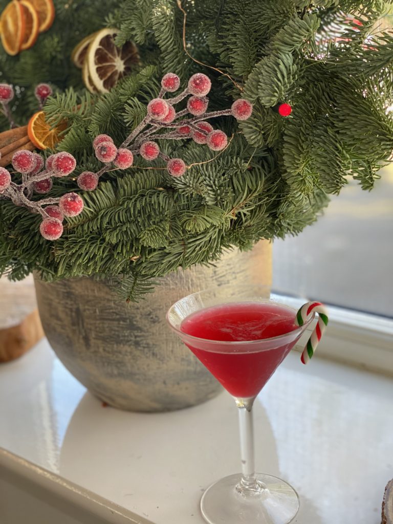 festive cocktail in a martini glass with a little candy cane as decoration