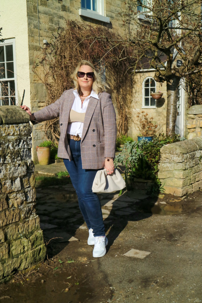 Lucy wearing a blazer, shirt, jeans and a knit bandau top